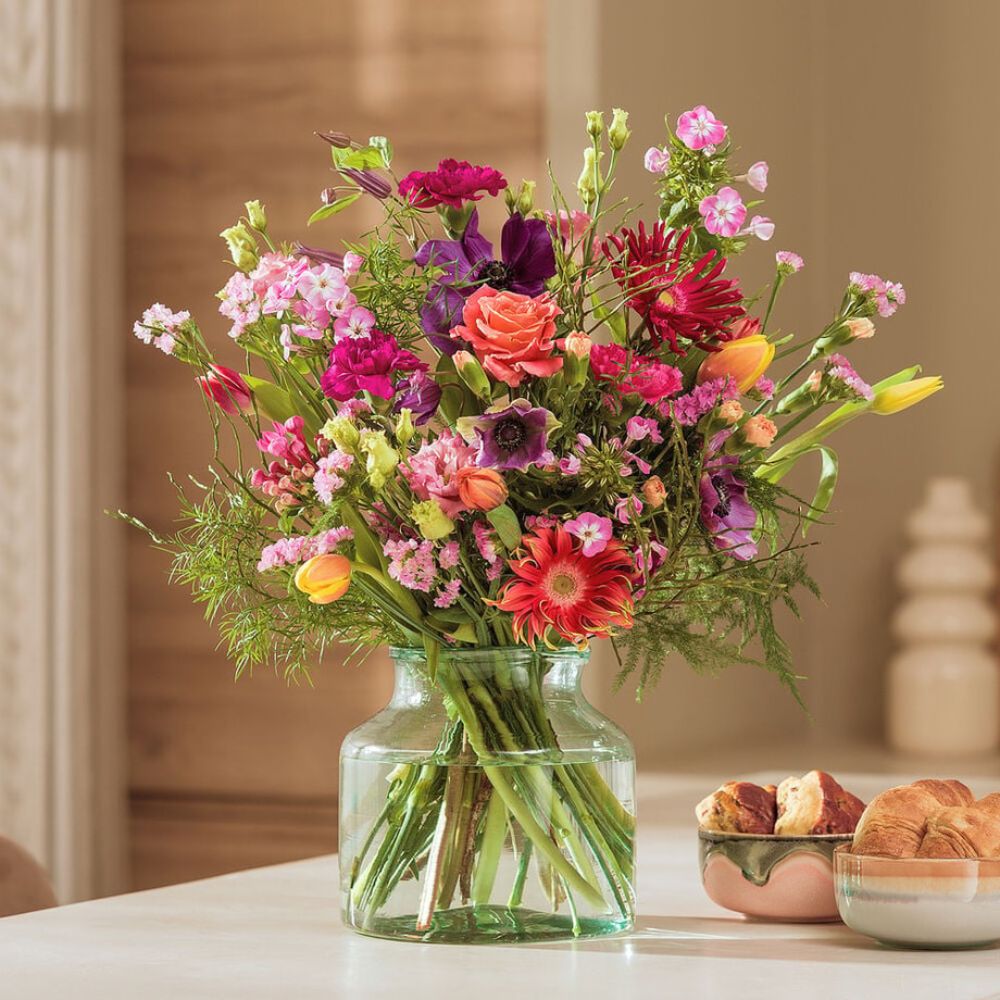 A colorful bouquet of flowers in a stylish vase on a kitchen table in Amsterdam